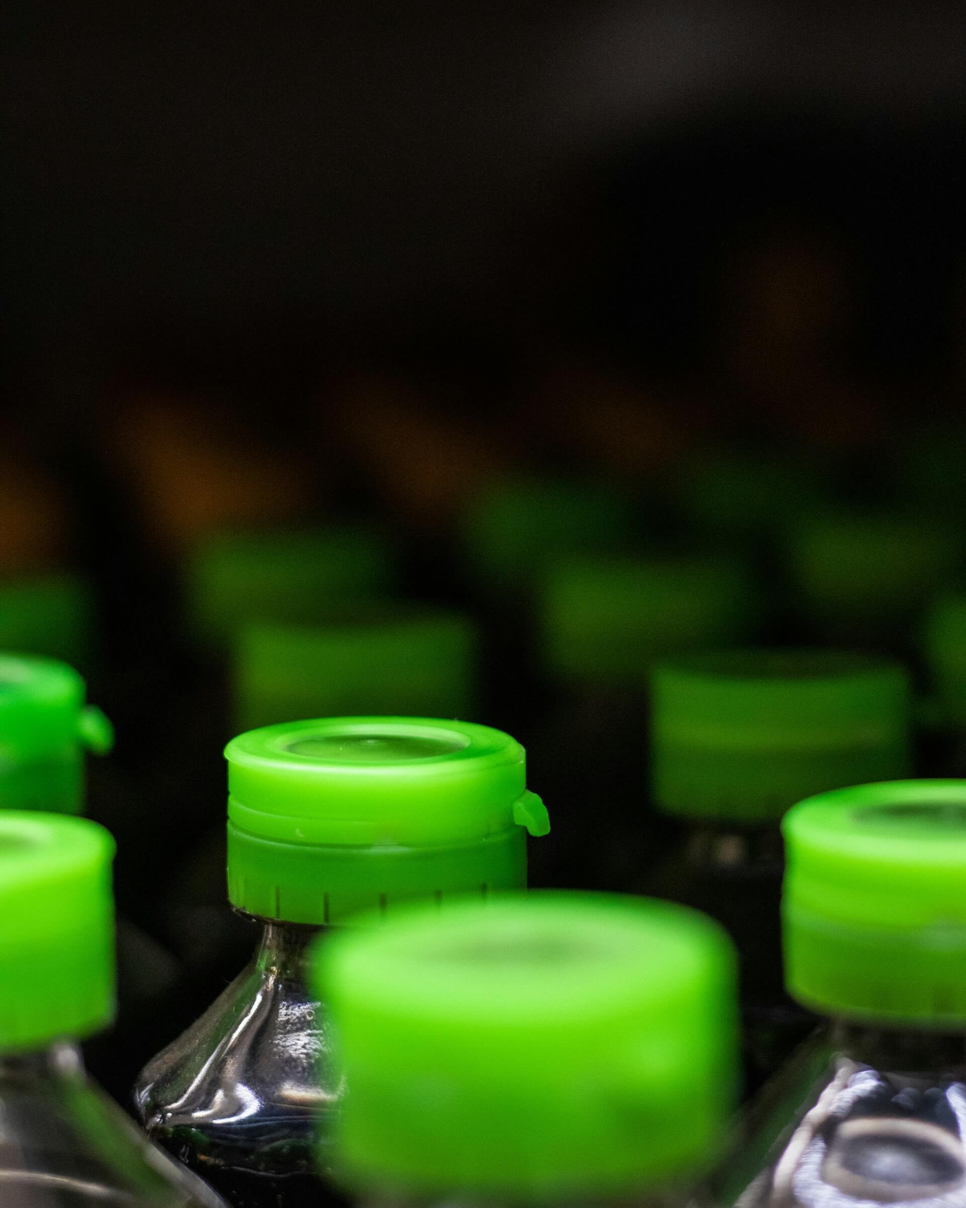Bouchons verts sur bouteilles plastique, illustration du greenwashing et des allégations de recyclabilité
